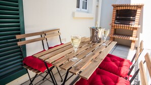 A wooden table with red cushions, a wine glass, and a bottle of champagne. - Luxury 2 bed apartment a few minutes walk from beach, harbour and town! (Torquay)