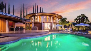 A resort with a swimming pool, lounge chairs, and a building with balconies.