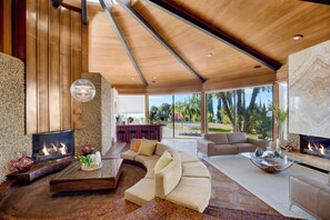 A modern living room with a fireplace, seating area, and a view of the outdoors.