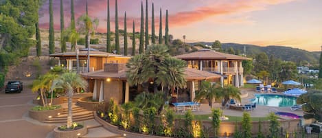 A resort with a pool, palm trees, and a sunset view.