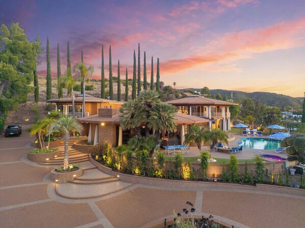 A resort with a pool, palm trees, and a sunset view.