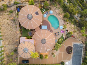 An aerial view of a resort with multiple large umbrellas, a swimming pool, and landscaped areas.