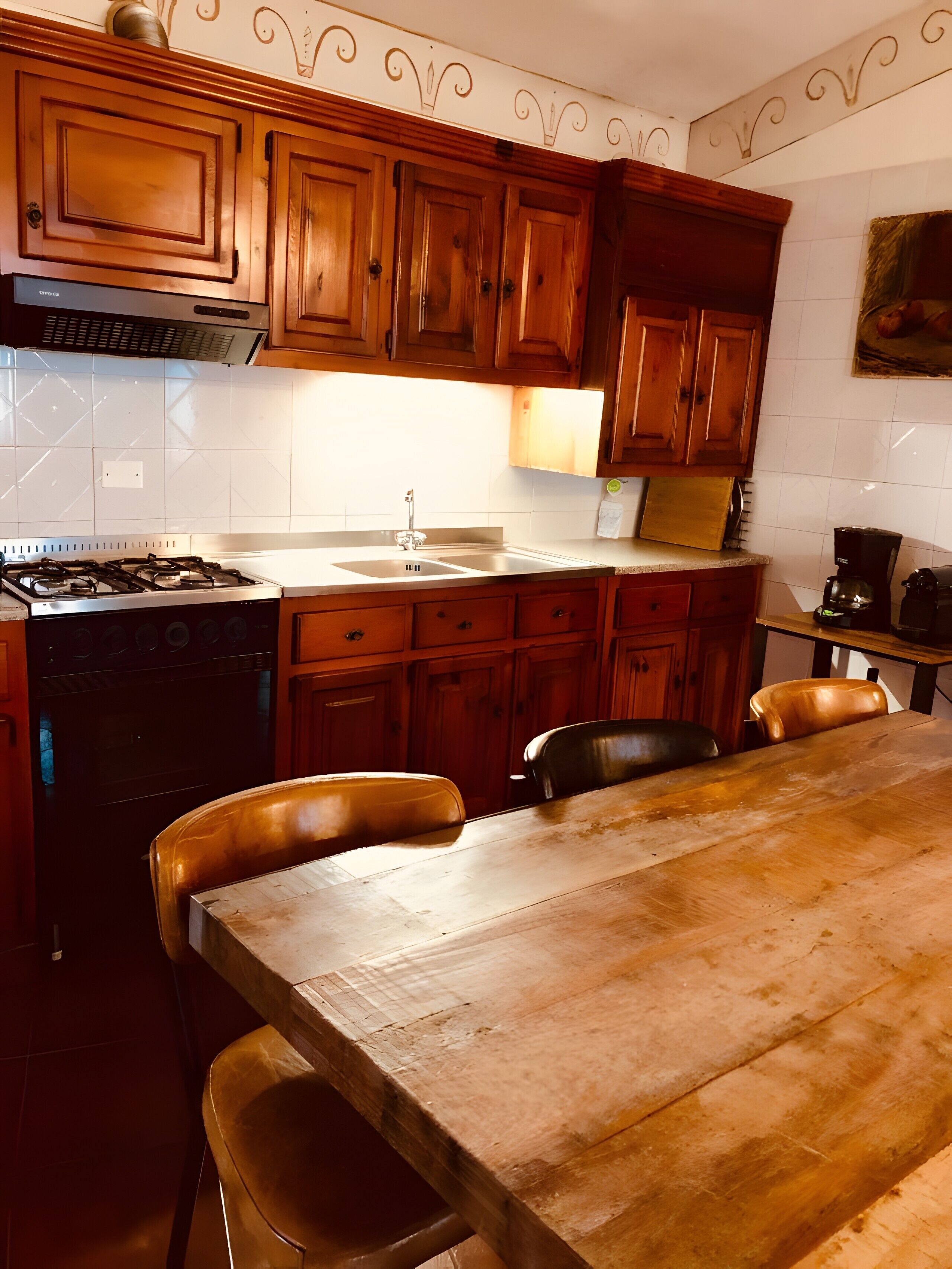 Une cuisine avec des meubles de rangement en bois, une cuisinière en acier inoxydable, un évier et une table à manger avec des chaises.