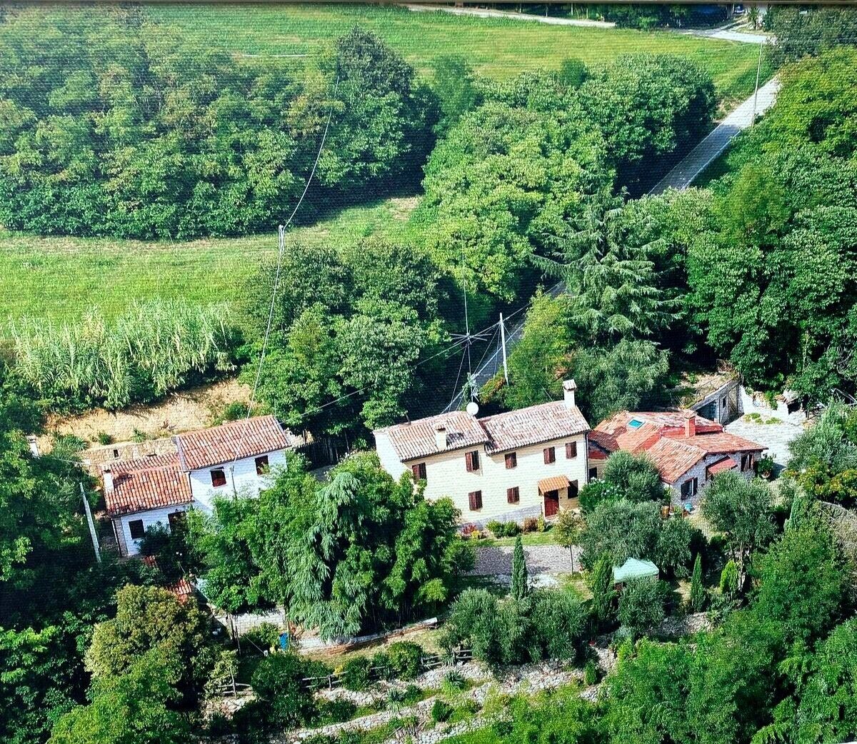 Ein ländliches Haus mit rotem Ziegeldach, umgeben von üppigem Grün und Feldern.