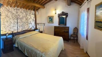 Un couloir étroit avec un lit, une commode, un miroir et un tableau accroché au mur.