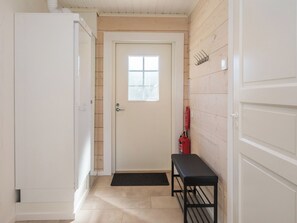 A narrow hallway with a white door, a black bench, and a fire extinguisher on the wall. - Kitkanvee 1 by Interhome (Kuusamo)