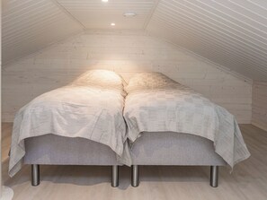 Un dormitorio tipo loft con techo inclinado y cama con cubrecama estampado.