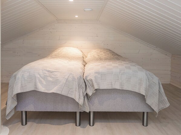 A loft bedroom with a sloped ceiling and a bed with a patterned bedspread.