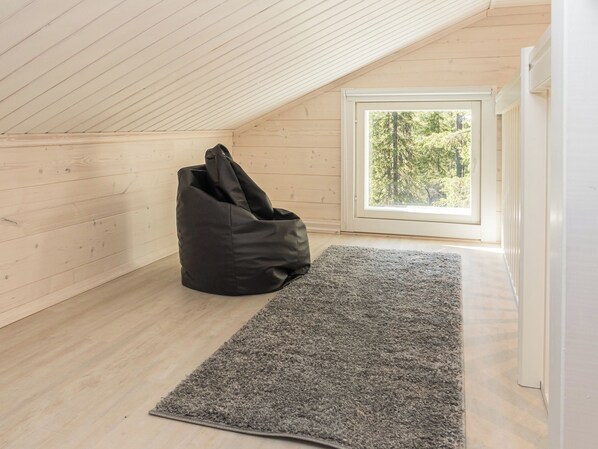 A room with a sloped ceiling, a large window, and a black bean bag chair.