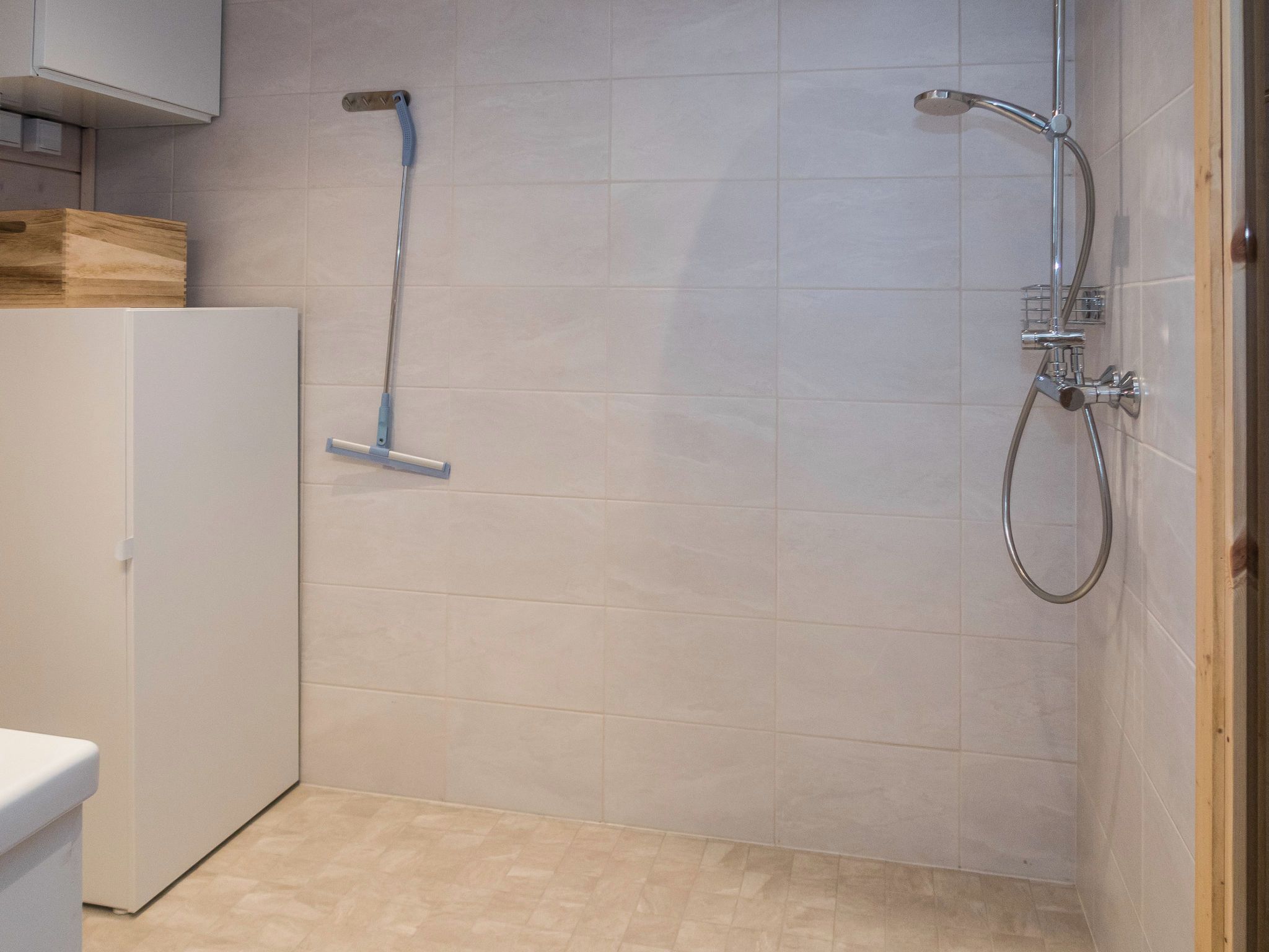 A bathroom with a shower, a toilet, and a cabinet.