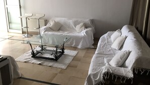 Una sala de estar moderna con una mesa de centro de cristal, dos sofás blancos y un radiador.