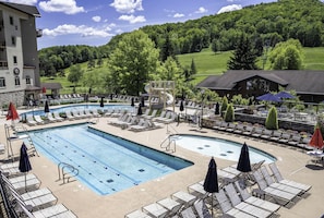 Un espace piscine avec des chaises longues, un toboggan et une vue sur un paysage verdoyant.