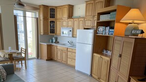 Una cocina compacta con armarios de madera, un refrigerador, un microondas y una zona de comedor con mesa y sillas.