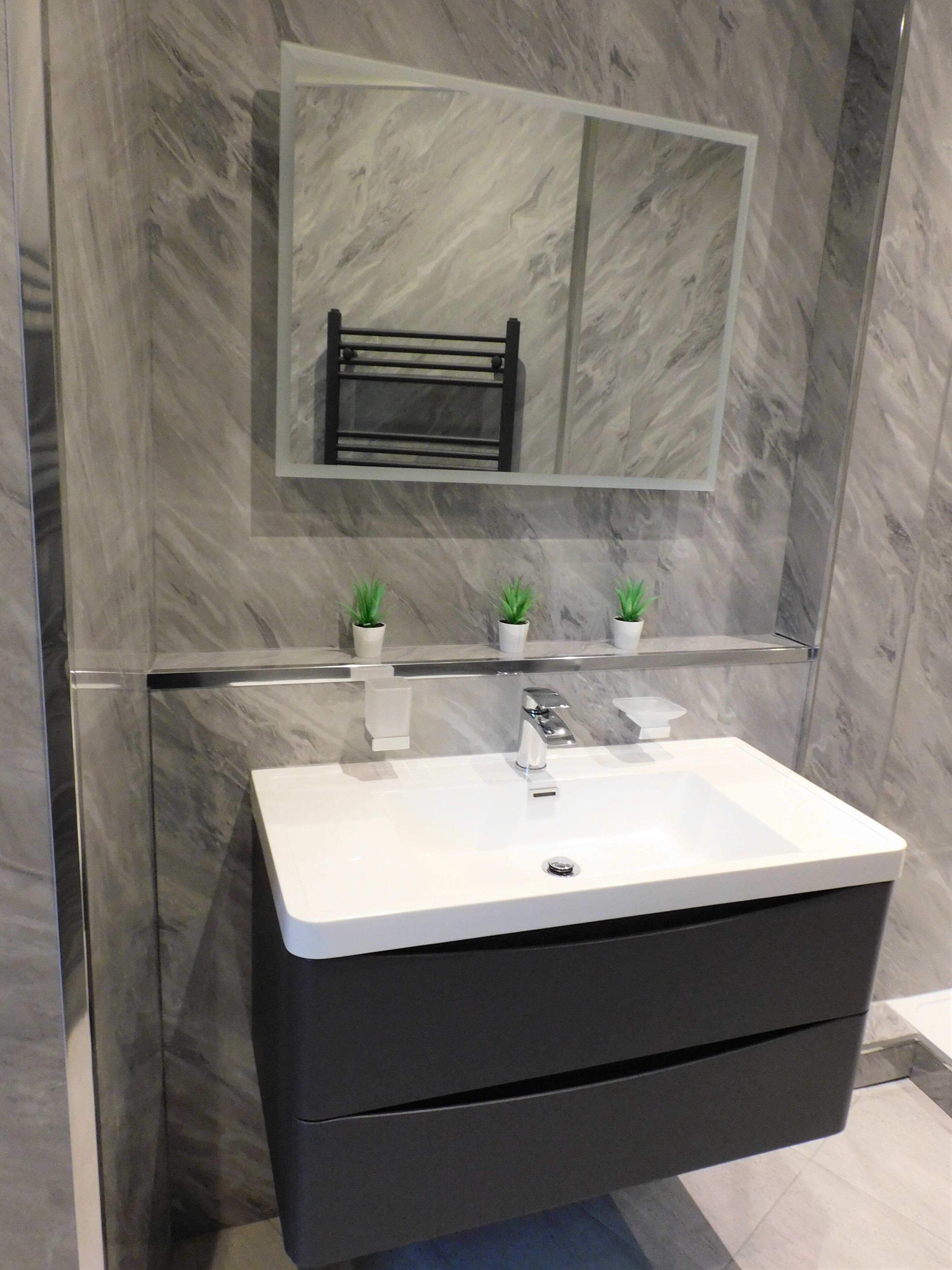A bathroom with a white sink, a mirror, and two potted plants.