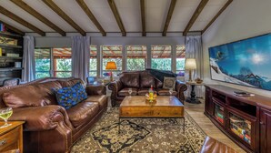 A spacious living room with leather sofas, a wooden coffee table, and a large painting on the wall. - Nana and Papa's Mountain Retreat by Kokopelli Property Management (Alto)