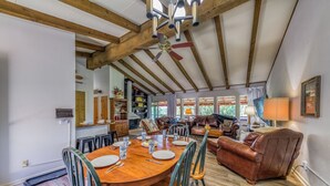 A spacious dining area with a wooden table and chairs, a ceiling fan, and a view of the kitchen and living room. - Nana and Papa's Mountain Retreat by Kokopelli Property Management (Alto)