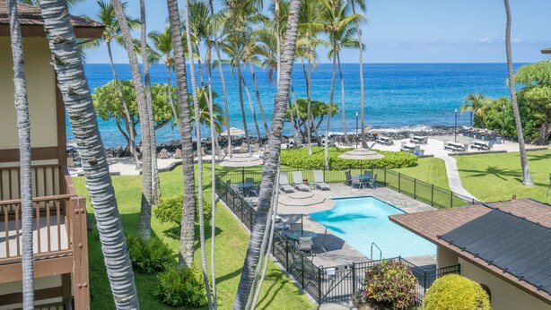 Un resort con piscina, lettini e palme.