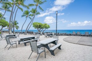 A beachside café with outdoor seating, palm trees, and a view of the ocean.