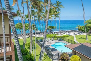 Un resort con piscina, sillones de descanso y palmeras.