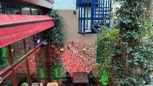 Un área de estar al aire libre con muros de ladrillo, plantas en macetas y una verja azul.