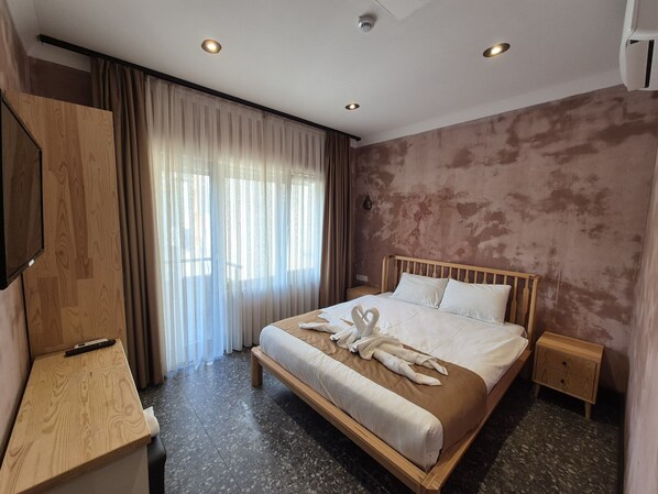 A hotel room with a wooden bed, a bedside table, a TV, and a large window with curtains. - BKM Mutfak Hostel (Istanbul)