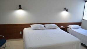 A hotel room with two single beds, a wooden headboard, two bedside tables with lamps, and a chair. - Hotel Imperio (Aparecida do Taboado)