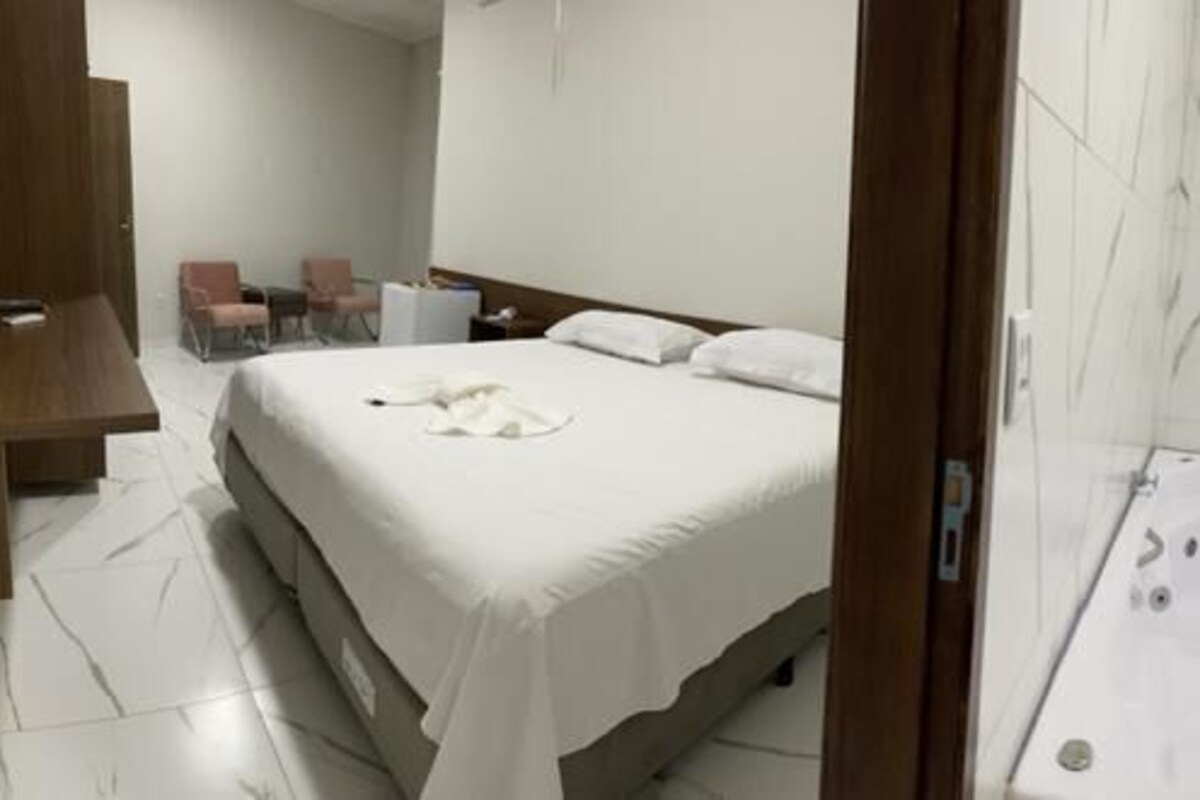 Una habitación de hotel con una cama, un baño con bañera, inodoro y lavamanos.