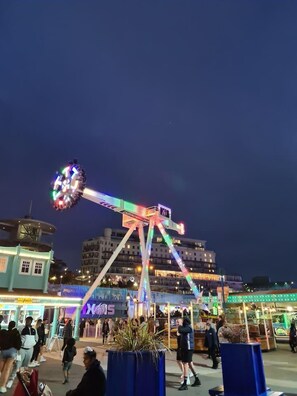 Een reuzenrad 's nachts met kleurrijke verlichting, omringd door gebouwen en mensen.
