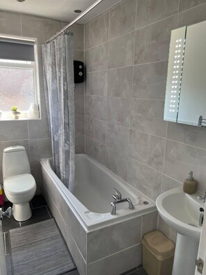 Een moderne badkamer met een badkuip, toilet en wastafel.
