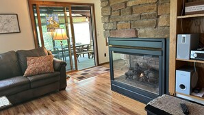 Ein Wohnzimmer mit Kamin aus Stein, einer Ledersofa und Holzboden.