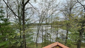 Eine Holzterrasse mit Blick auf einen von Bäumen gesäumten See.