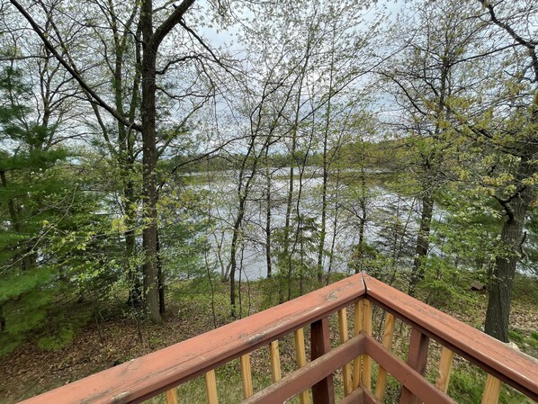 A wooden deck with a view of a lake surrounded by trees.