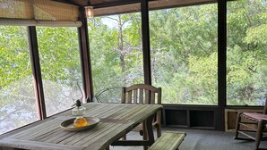 Ein Holzespeisesaal mit Bänken, großen Fenstern und Blick auf Bäume.
