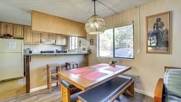Une cuisine moderne avec des meubles en bois, un grand îlot central agrémenté de sets de table roses, un banc et un coin repas.