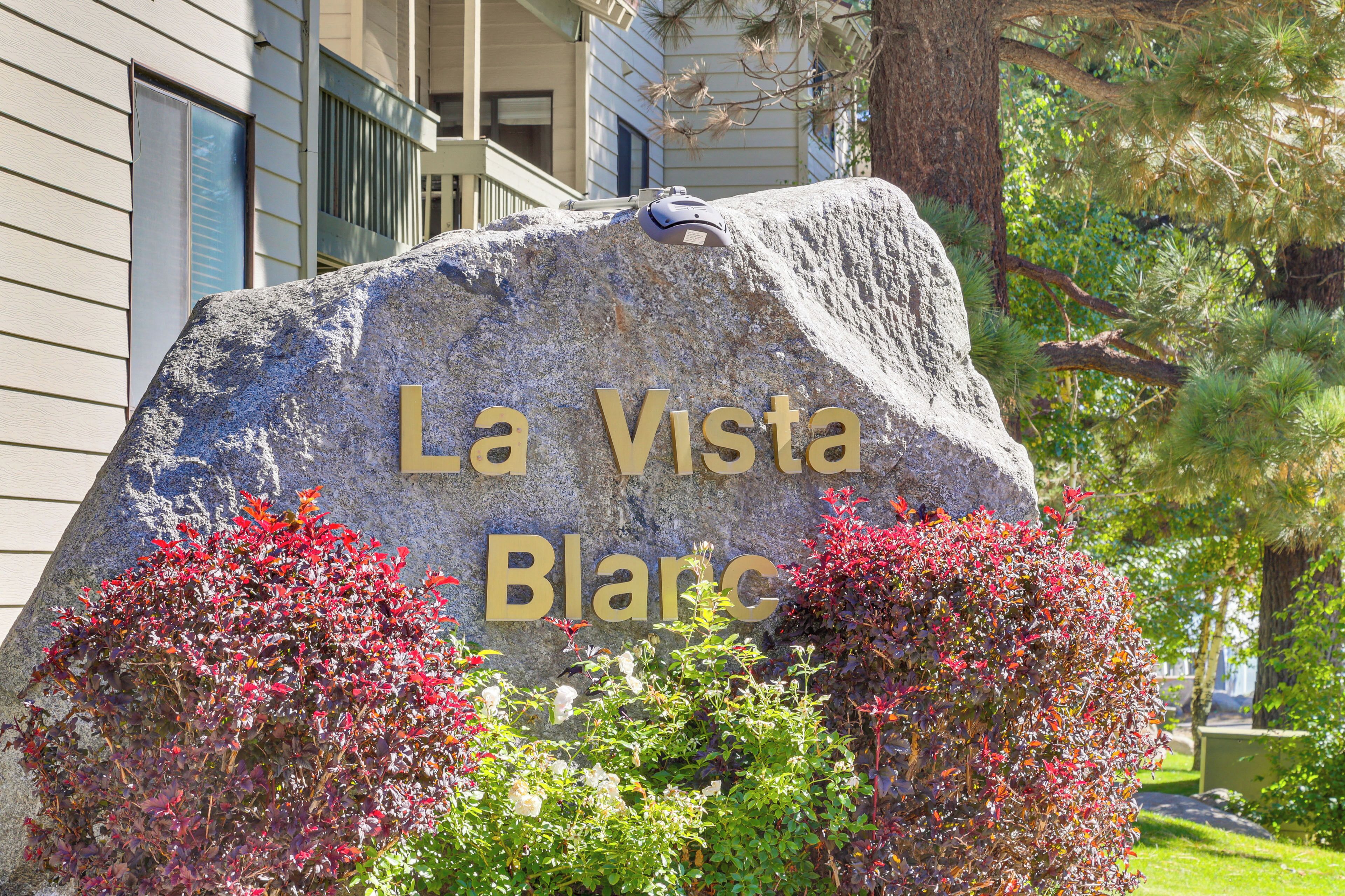 A large stone sign with "La Vista Blanca" engraved on it, surrounded by lush greenery.