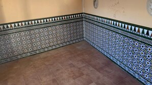A corner room with patterned tile walls and floor, a window with curtains, and a wall-mounted light fixture. - terraced house (Marbella)