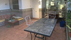 A patio area with a metal table and chairs, a sofa, and a tiled wall with a decorative border. - terraced house (Marbella)