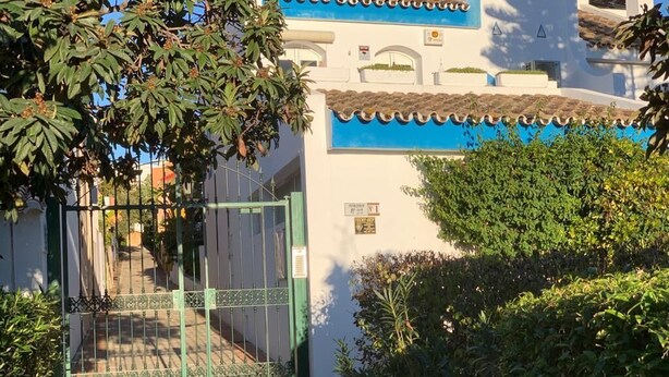 A gated entrance to a building with a tiled roof and a blue trim. - terraced house (Marbella)