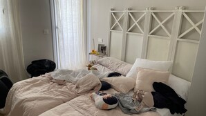 A neatly made bed with a white headboard, a bedside table with a lamp, and a window with sheer curtains. - terraced house (Marbella)