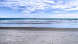 Een strand met een heldere lucht en een rustige zee.
