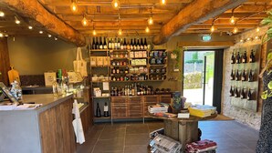 A cozy interior with wooden beams, a variety of wine bottles on shelves, and a small table with books and blankets. - Hot Tub Heaven in Beautiful Village, Close to Beaches - Blue Flag & Dog Friendly (Stoke Gabriel)