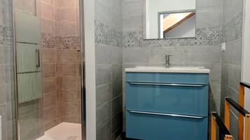 Un baño con ducha, lavamanos y espejo.