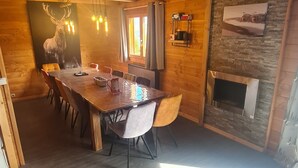 A wooden interior with a dining table, chairs, a chandelier, a fireplace, and a stone wall. - CHALET 12-14 Persons 200 Metres from the slopes (Fontcouverte-la-Toussuire)