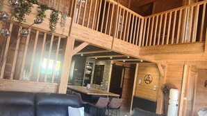 A spacious living area with a black leather sofa, a white coffee table, and a wooden ceiling with a fan. - CHALET 12-14 Persons 200 Metres from the slopes (Fontcouverte-la-Toussuire)