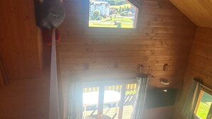 A cozy cabin with a wooden interior, a sofa, a small table, and a view of a village through a window. - CHALET 12-14 Persons 200 Metres from the slopes (Fontcouverte-la-Toussuire)