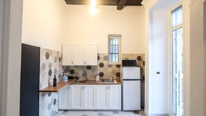 Une cuisine de taille réduite avec des meubles blancs, un four à micro-ondes, un évier et une fenêtre.