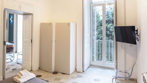 Une chambre d’hôtel avec un grand lit, une télévision, un balcon avec vue et une porte donnant sur une autre chambre.