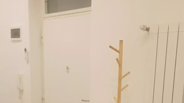 A room with a white door, a coat rack with a wooden coat, and a radiator. - Private new flat (Bari)