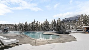 A snow-covered outdoor pool area with lounge chairs and a mountain backdrop. - Luxury Moonlight Basin 2 Bedroom Condo (Big Sky)