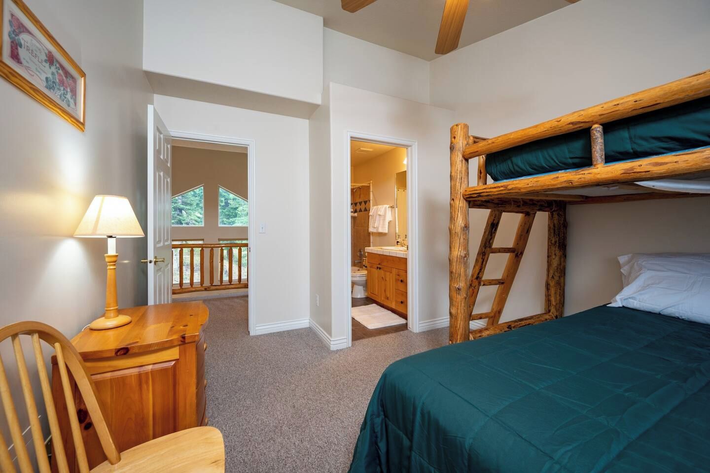 A room with a bunk bed, a desk with a lamp, and a view of a balcony.